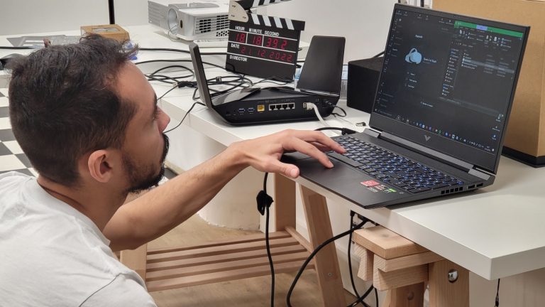 Homme manipulant un ordinateur portable, travaillant sur un projet technique dans un espace de bureau.